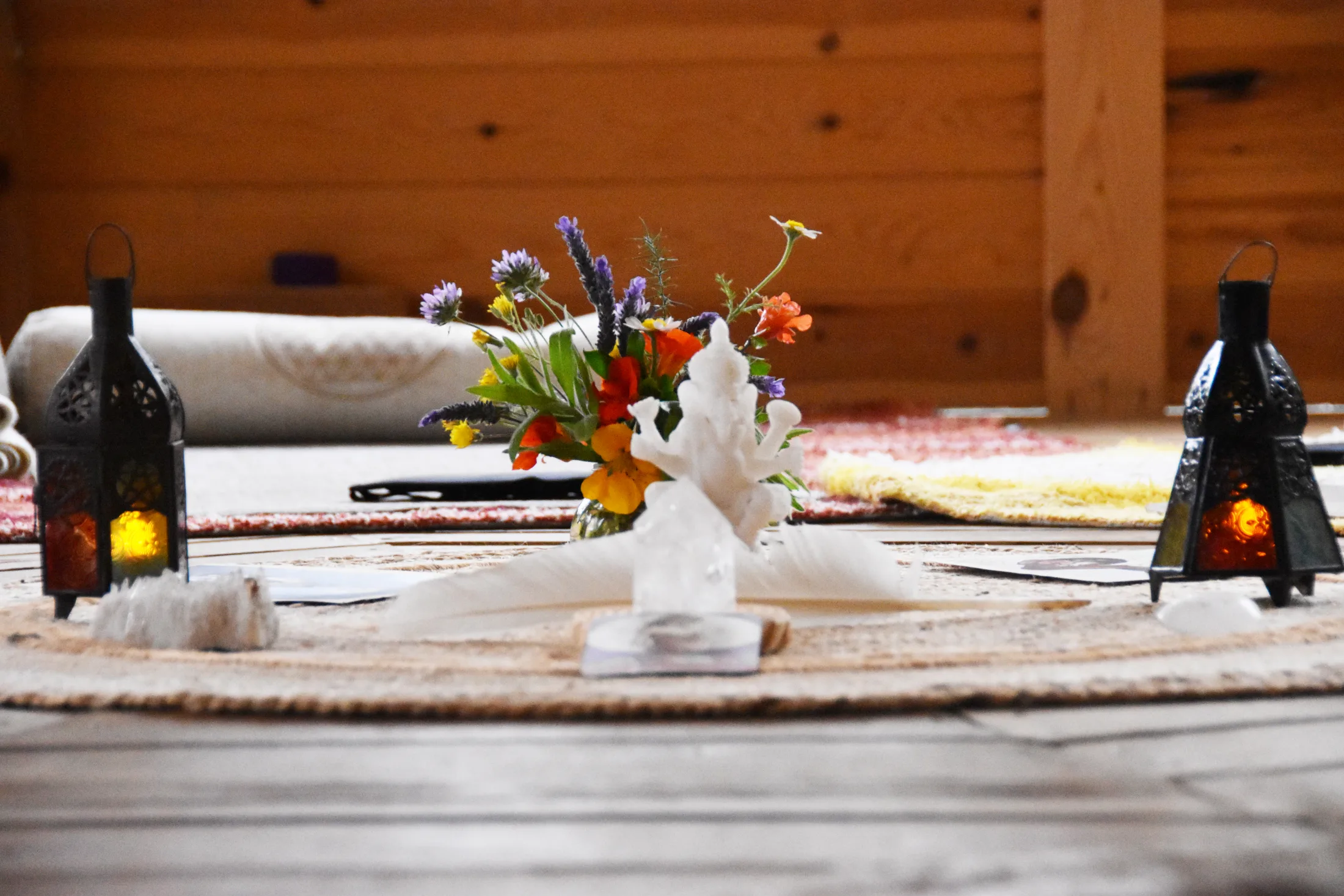Allestimento per una pratica meditativa: fiori di campo, lanterne e cristalli su un tappeto